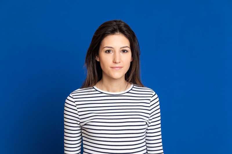Portrait of beautiful young woman against blue background