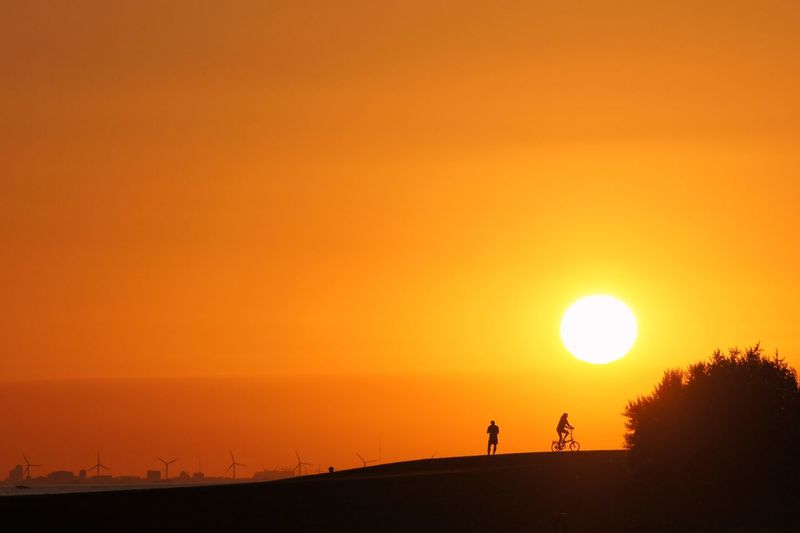 Silhouette man on landscape against orange sky