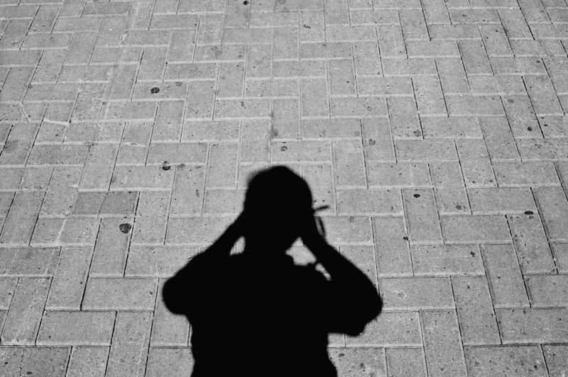 High angle view of silhouette woman standing on cobblestone street