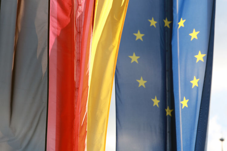 The german and eu flags hanging side by side on a sunny day