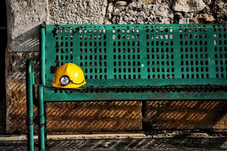 Yellow hardhat with headlamp on bench during sunny day