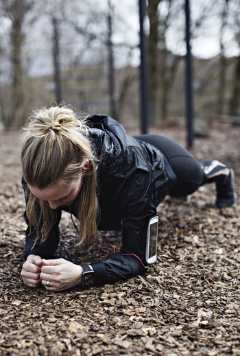 Female athlete performing plank position in forest