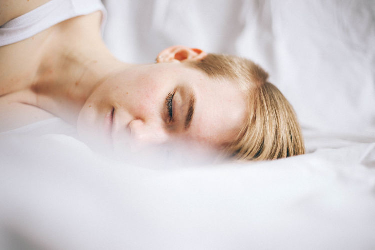 CLOSE-UP OF YOUNG WOMAN SLEEPING ON BED