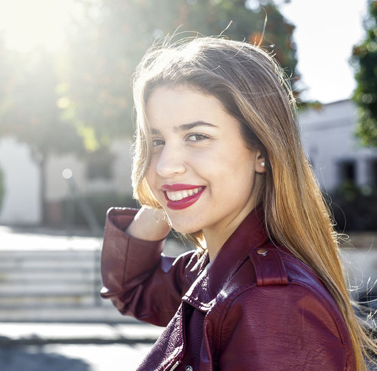 Smiling young woman wearing maroon jacket
