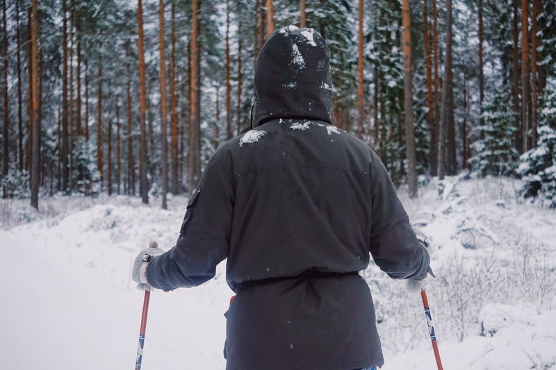 Rear view of person skiing in snow covered forest