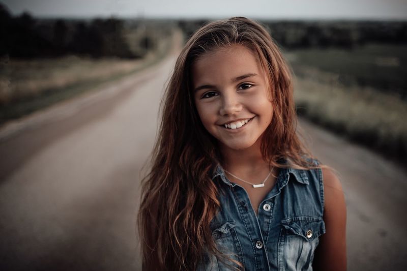 Portrait of girl standing on road at sunset
