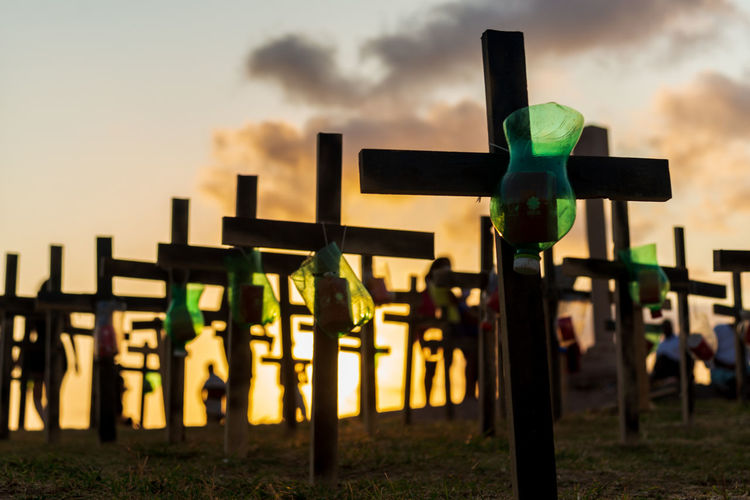 Silhouette of people and crosses fixed on the ground in honor of those killed by covid-19. 