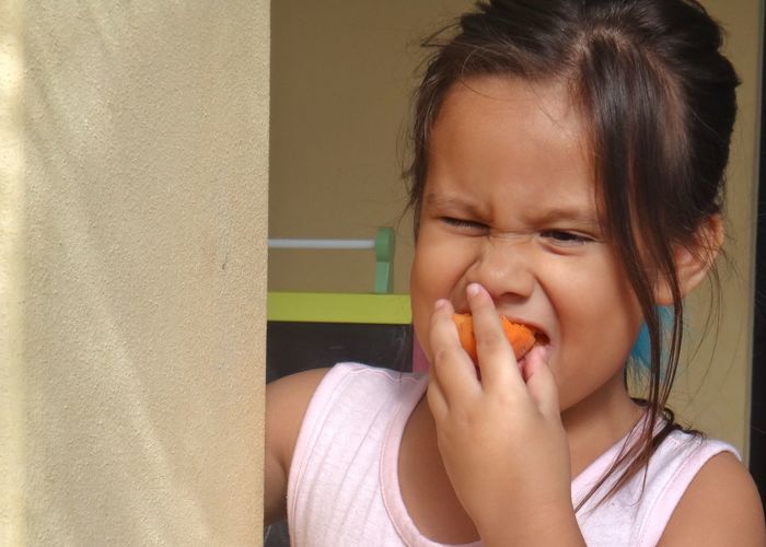 Cute girl eating apricot at home