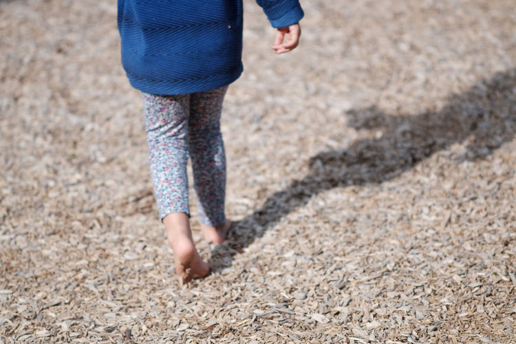 Rear view of girl walking on wood chips