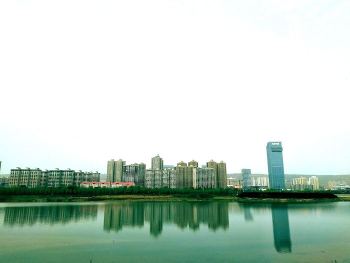 River by buildings against clear sky
