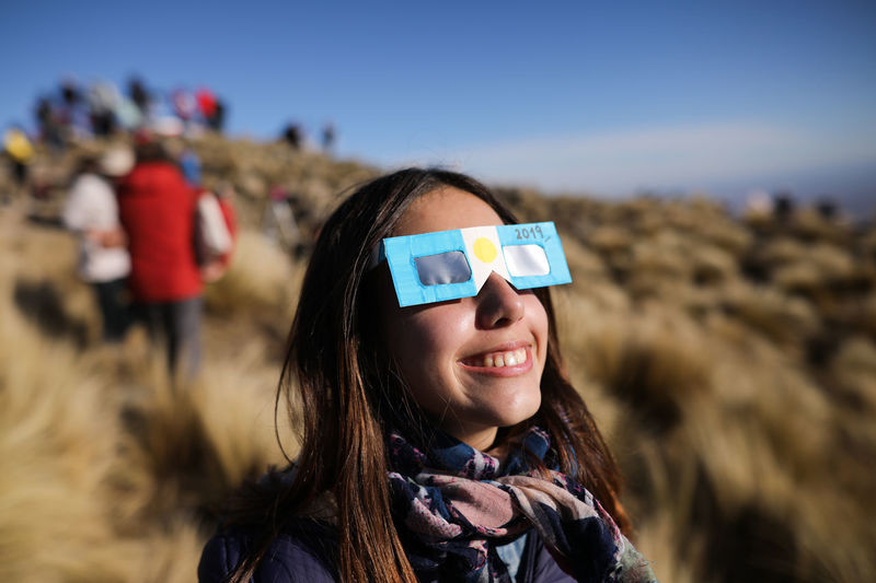 Smiling teenage girl wearing 3-d glasses outdoors