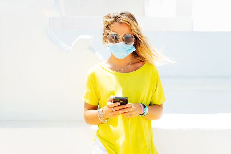 Woman smart phone looking away while standing ,with mask.