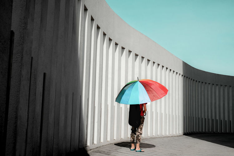 Rear view of a boy with umbrella standing on driveway