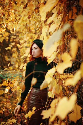 Full length of woman standing amidst leaves in forest