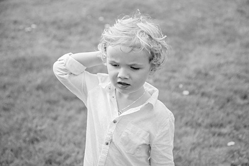 Cute boy looking away while standing on field