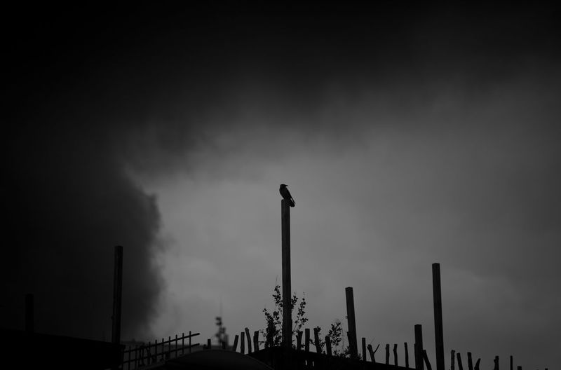 Low angle view of silhouette smoke stack against sky