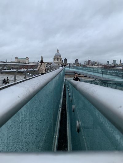 View of bridge in city against cloudy sky
