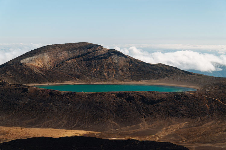 Turquoise blue water in a crater of a volcano surrounded by clouds in tongariro new zealand.