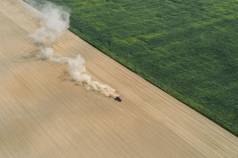 Aerial shot of farmer with a tractor on the agricultural field sowing. 