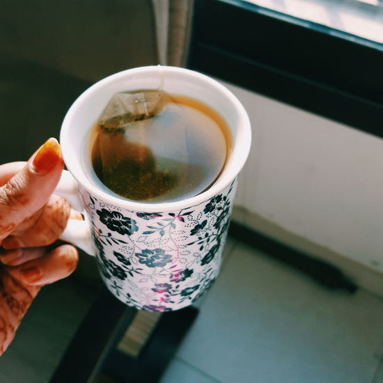Cropped hand of woman holding tea cup at home