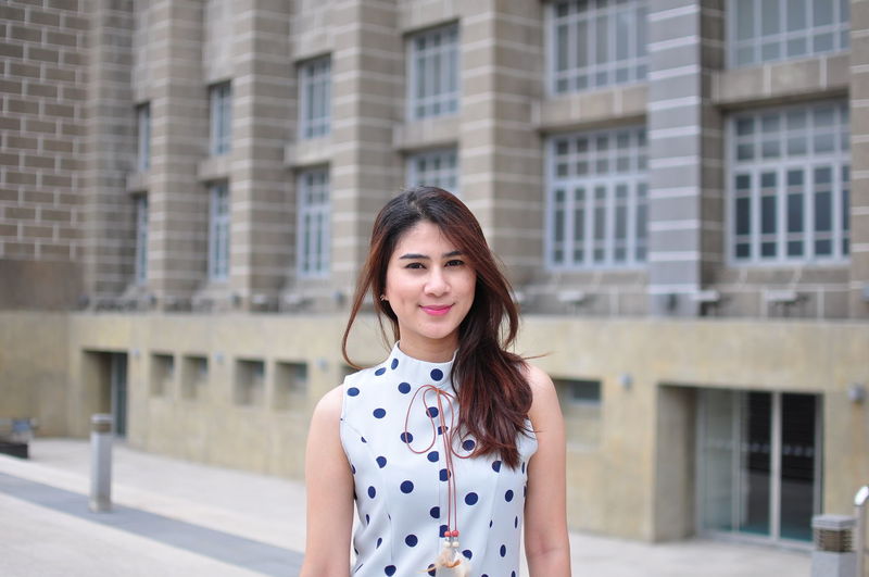 Portrait of smiling woman standing against building in city