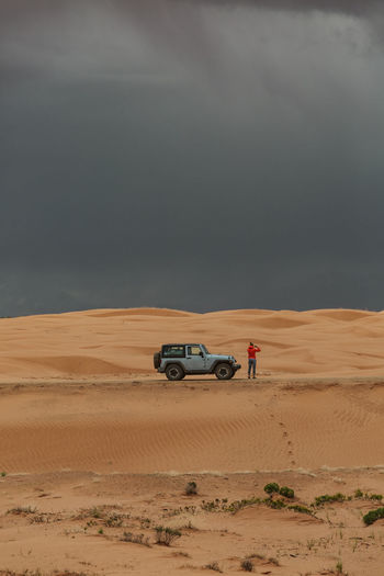Woman gets out of her jeep to take pictures of desert microburst