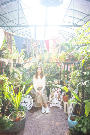 Portrait of woman with potted plants in greenhouse