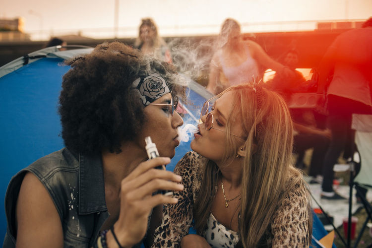 Couple smoking together outside tent at musical event