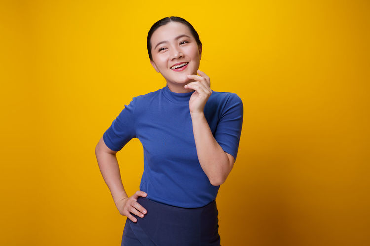 Portrait of beautiful young woman against yellow background