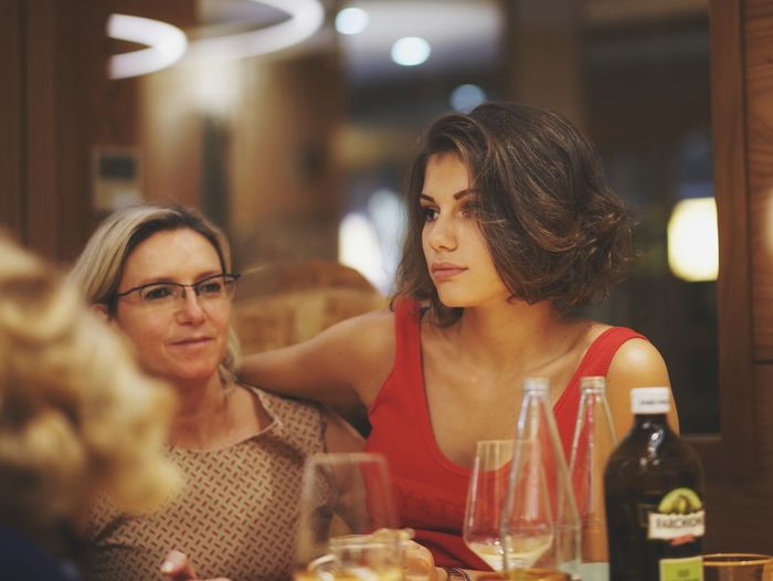 Mother and daughter looking away while sitting at restaurant