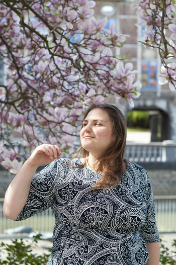 Portrait of a beautiful plump caucasian confident woman in magnolia flowers