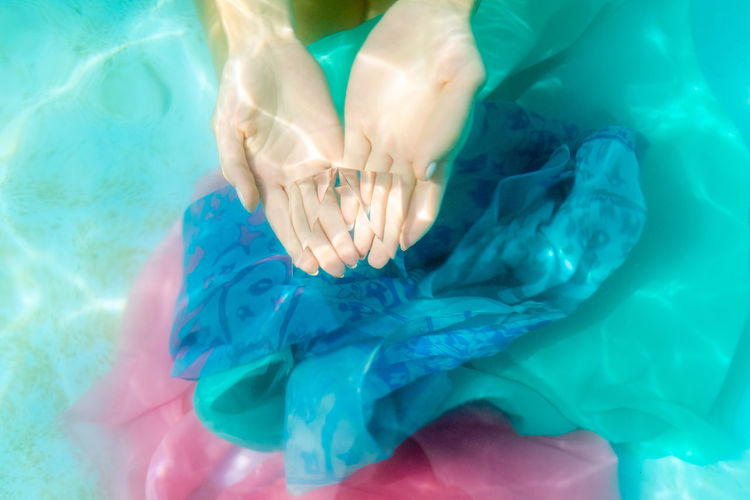 Cropped hand of woman holding pyramid crystal in swimming pool