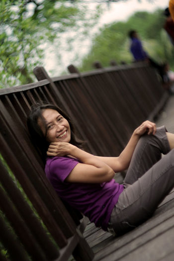 Portrait of a smiling young woman sitting on railing