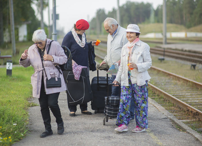 Group of positive elderly seniors people waiting train before traveling during a pandemic
