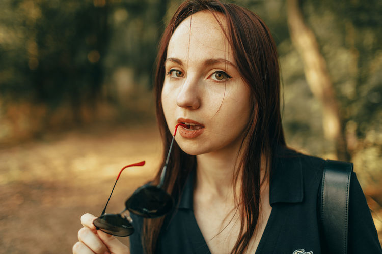 Close-up portrait of young woman blowing dandelion