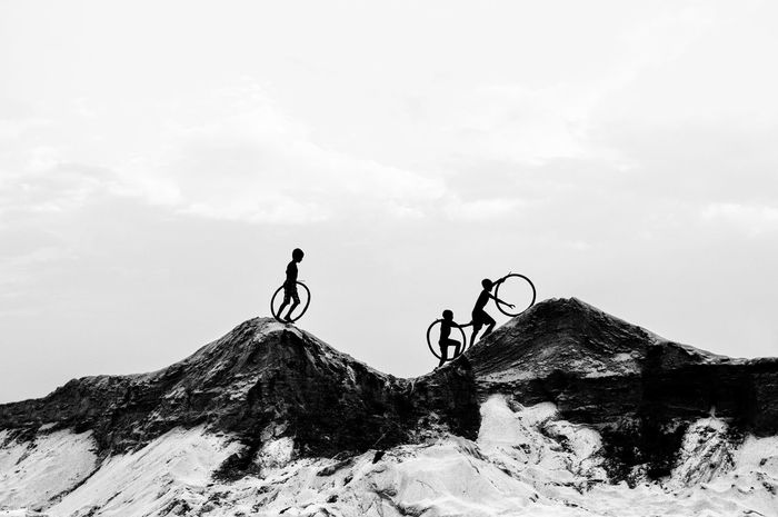 PEOPLE RIDING BICYCLE ON MOUNTAIN AGAINST SKY