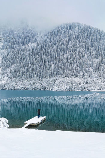 A man stands on the boat pier of a mountain lake in winter. winter landscape.