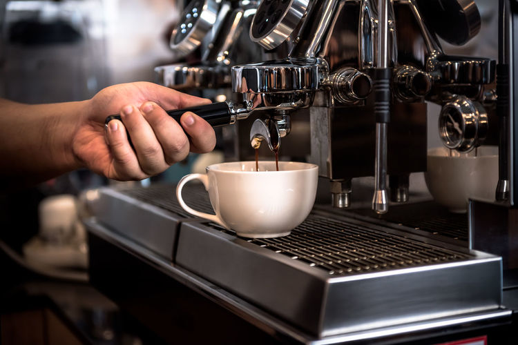 Cropped image of hand pouring coffee in cafe