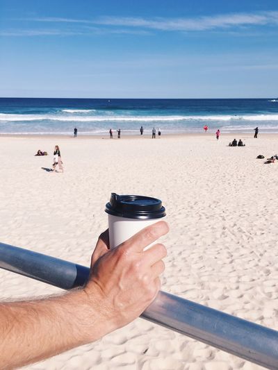 Cropped image of man holding drink at beach