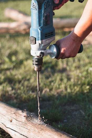 Close-up of carpenter drilling on wood