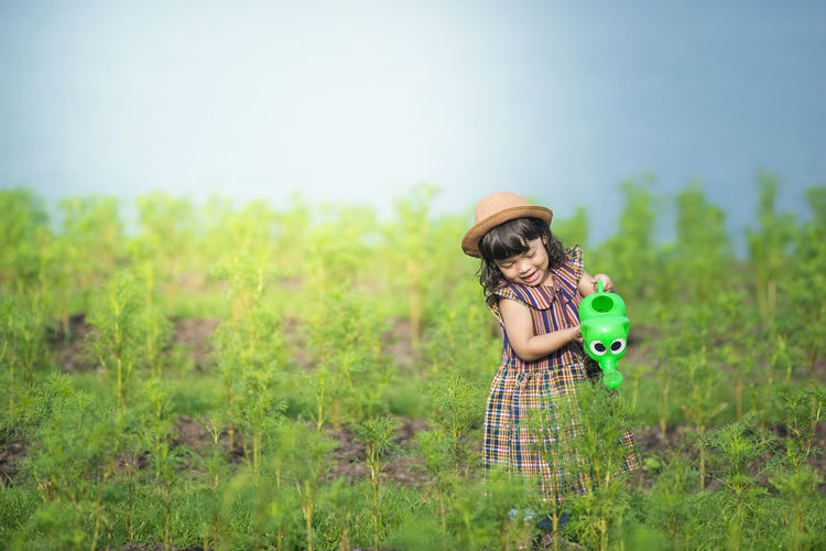 Girl watering plants on field