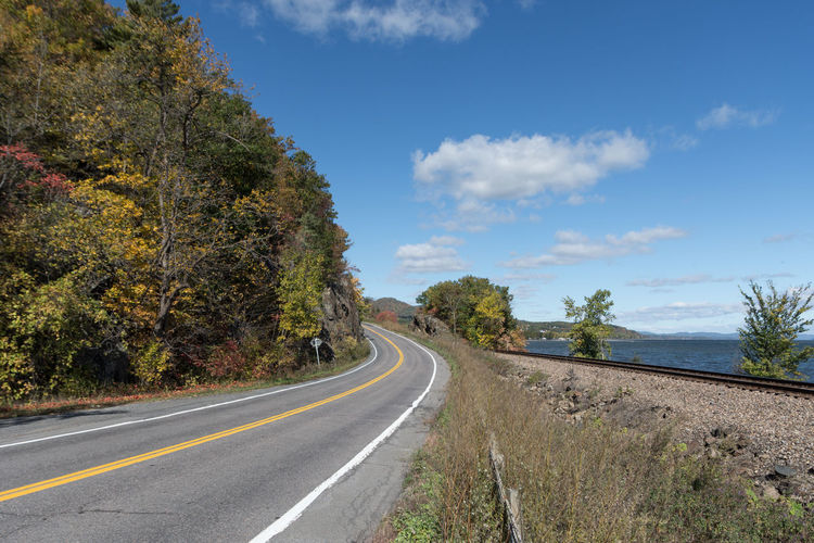 Empty road along trees and blue sky