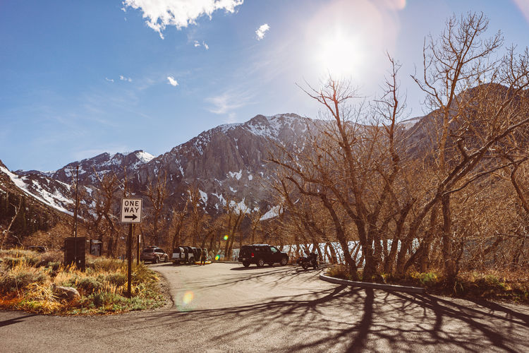 Road amidst trees and mountains against sky