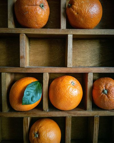 Oranges on a wooden shelf.  the background