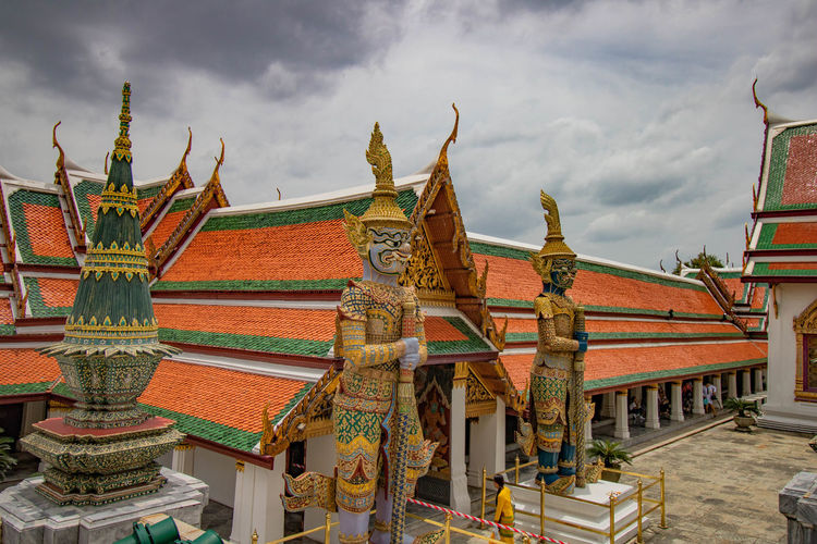 Statues and temple against cloudy sky