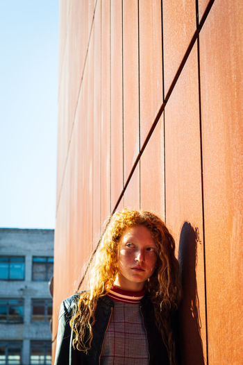 Young woman leaning on wall