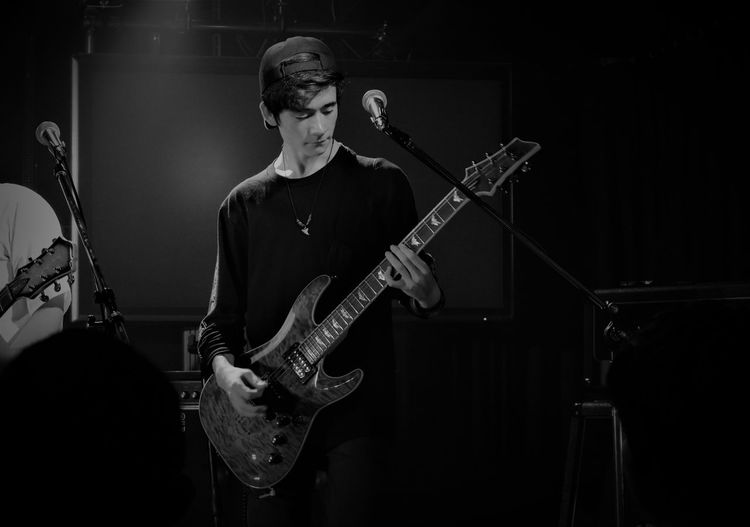 Young man playing electric guitar on stage