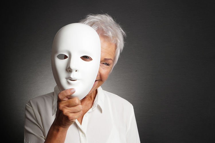 Portrait of person holding mask against white background