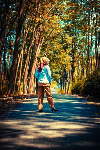 Full length of girl walking on road in forest