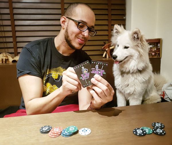 Man playing card with dog at home
